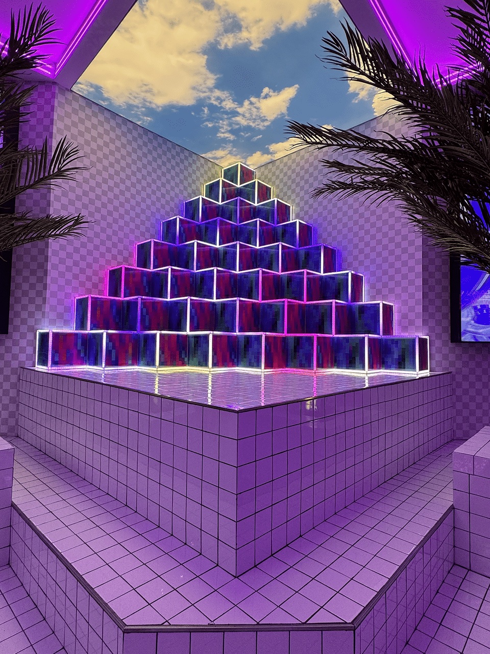 Purple pyramid of illuminated glass cubes with palm trees and faux sky